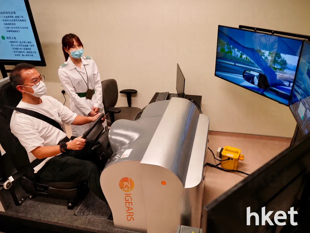 An iGears colleague demonstrates the driving simulator at Kwai Chung Hospital alongside a healthcare professional; the equipment logo has been edited to iGears.